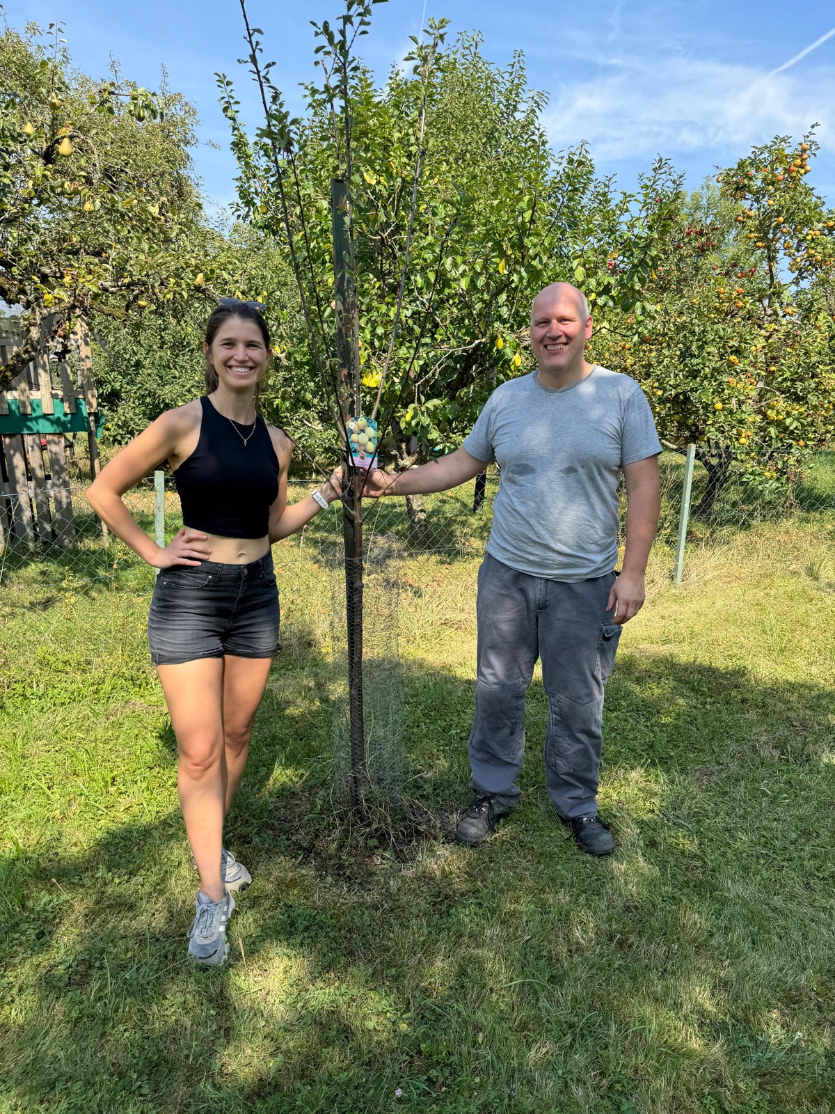 Carina und Mathias neben einem frisch gepflanzten jungen Obstbaum